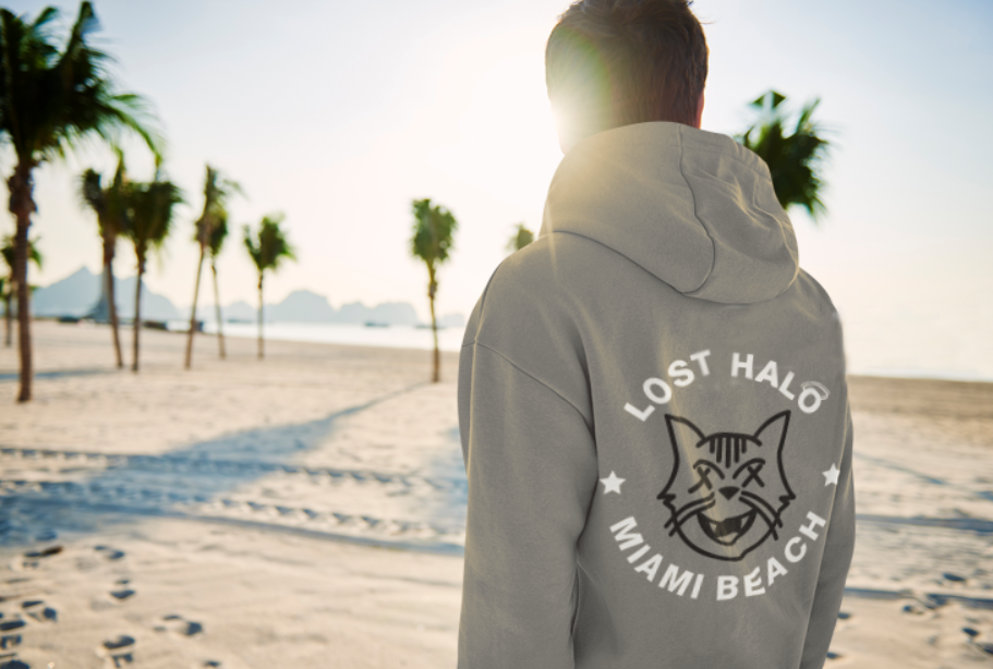 Man on sunny beach wearing a hoodie with Lost Halo graphic logo on back